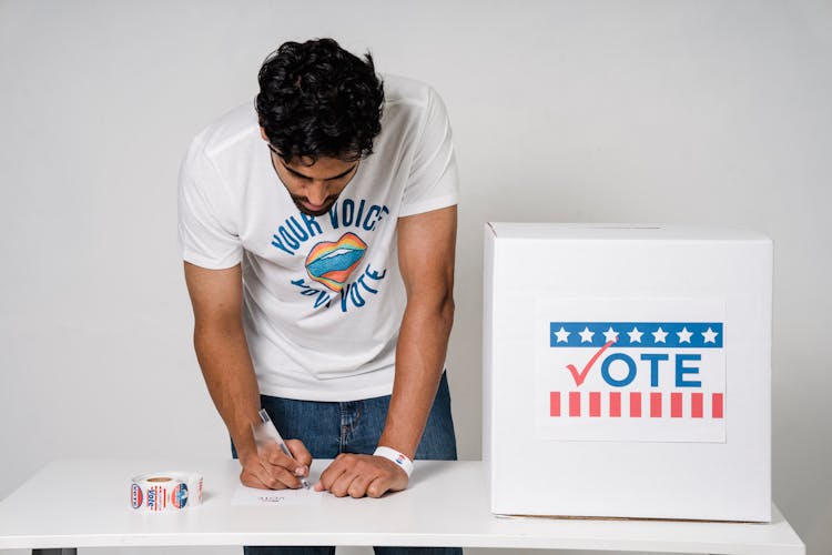 A Man Writing On A Ballot 