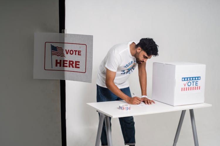 A Man Voting Beside A Ballot Box