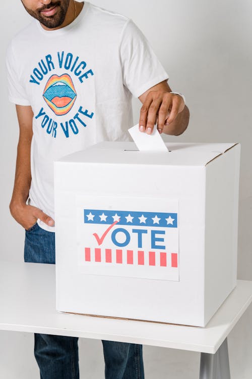 흰색 상자에 자신의 투표를 두는 사람의 사진