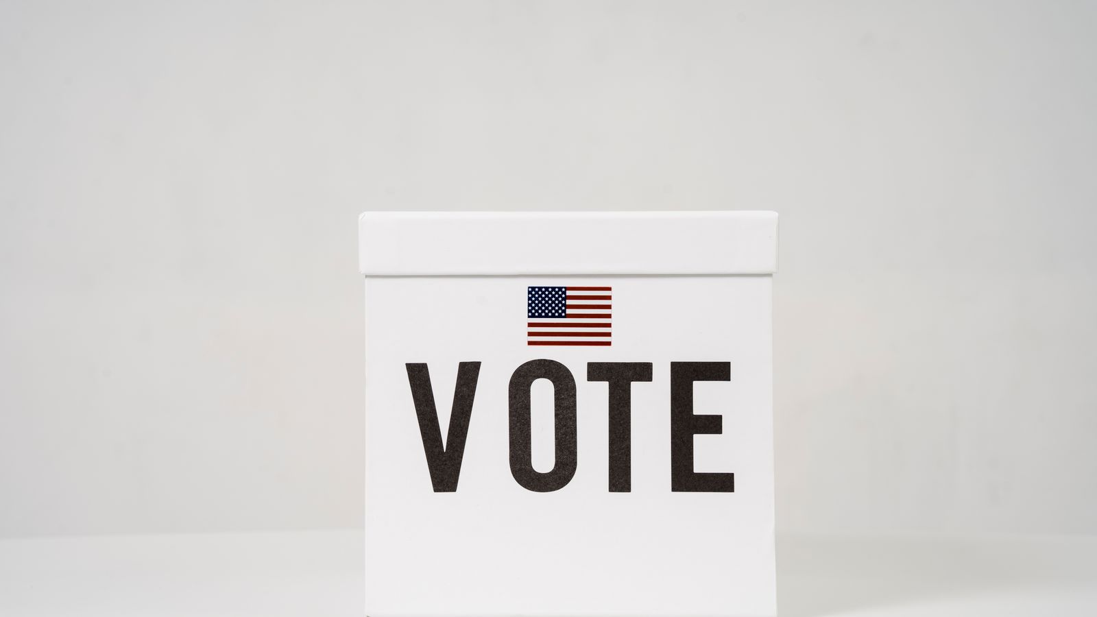 A minimalist ballot box with 'Vote' and an American flag, symbolizing elections.