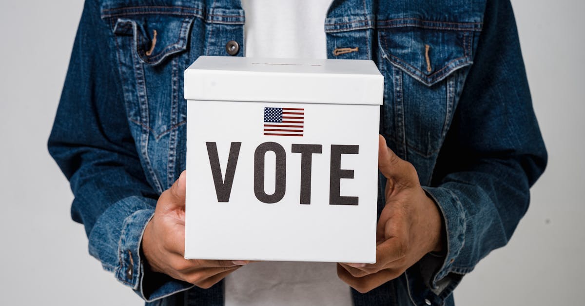 Photo by Sora Shimazaki Person in denim holding a ballot box with a US flag, emphasizing voting rights.