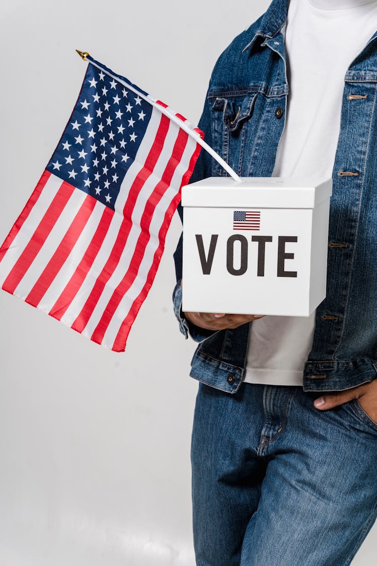 A Person Carrying A Ballot Box With A Country Flag