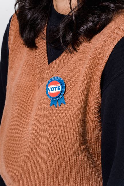 Photo by Sora Shimazaki A voter wearing a brown sweater displays a vote badge during election season.