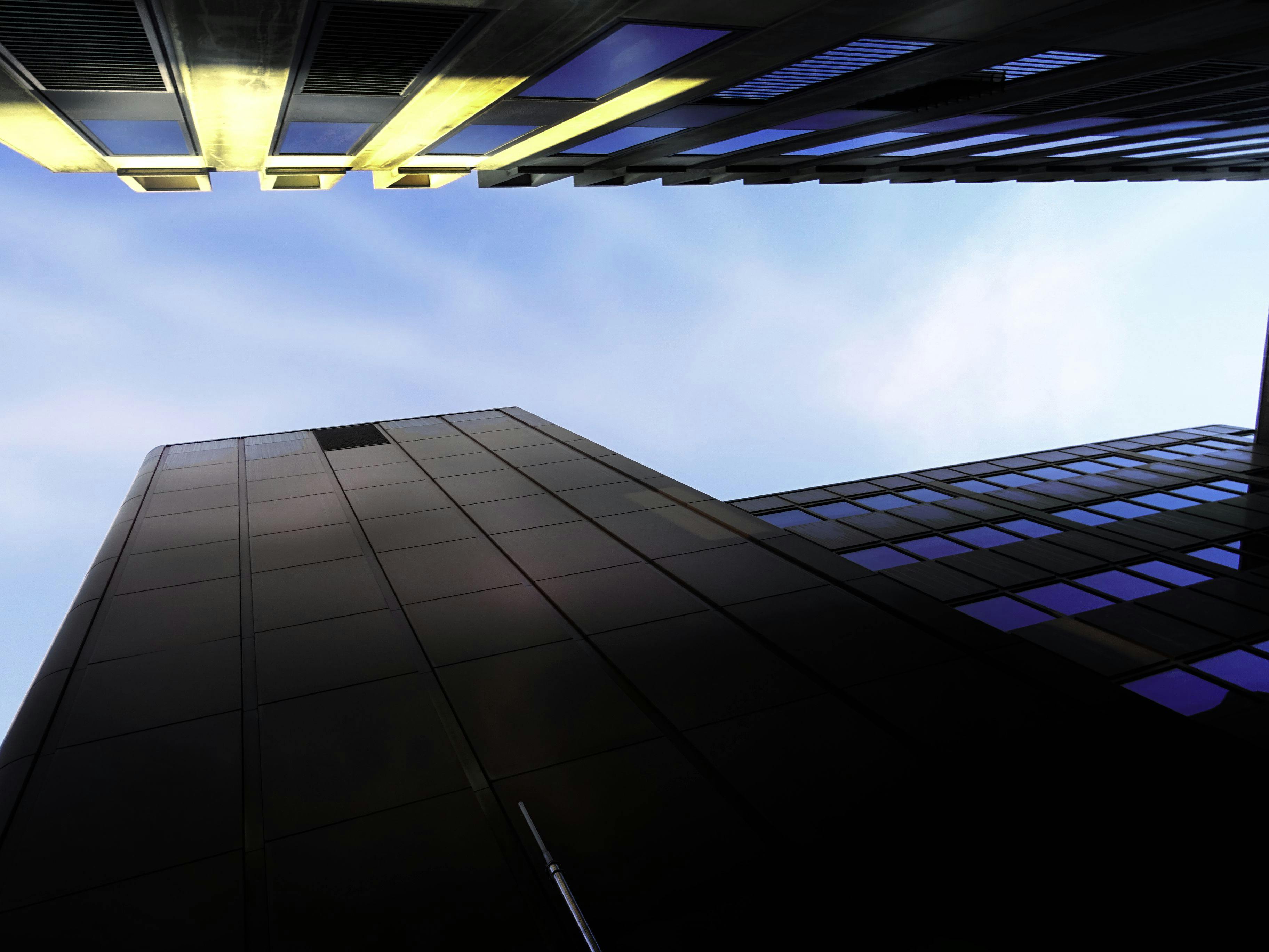 从低角度仰望现代摩天大楼，映衬着明亮的蓝天，景象十分壮观