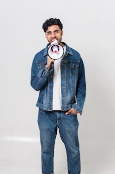 Stylish man in denim shouting through a megaphone in studio shoot.