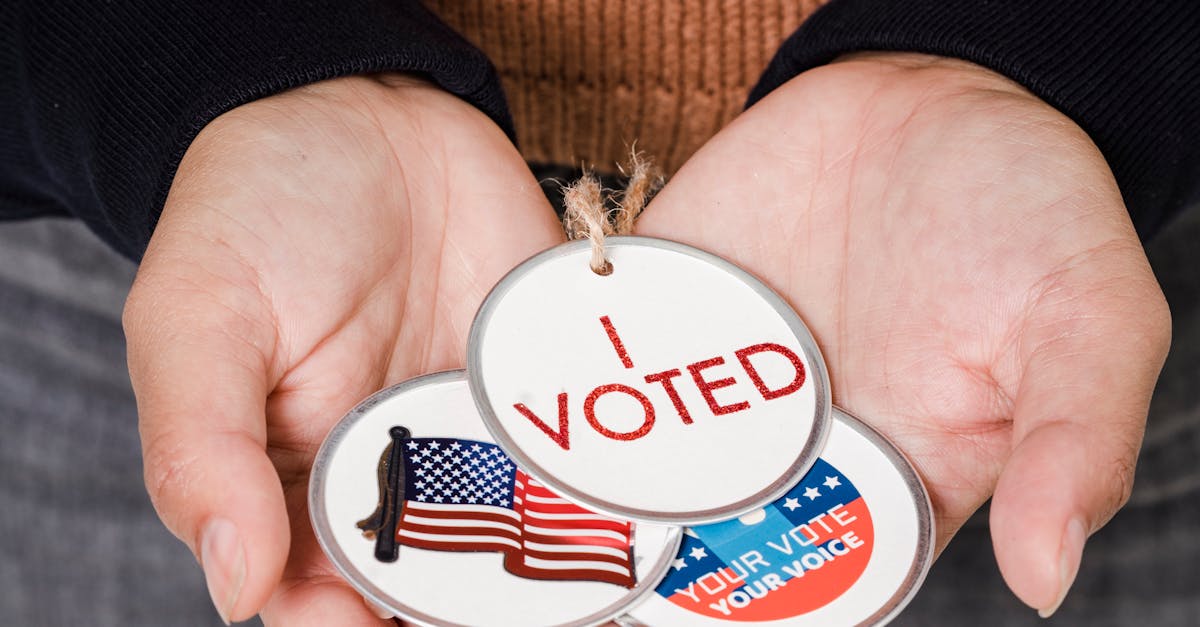 Photo by Sora Shimazaki Close-up of hands holding 'I Voted' badges with USA flag, symbolizing democratic participation.
