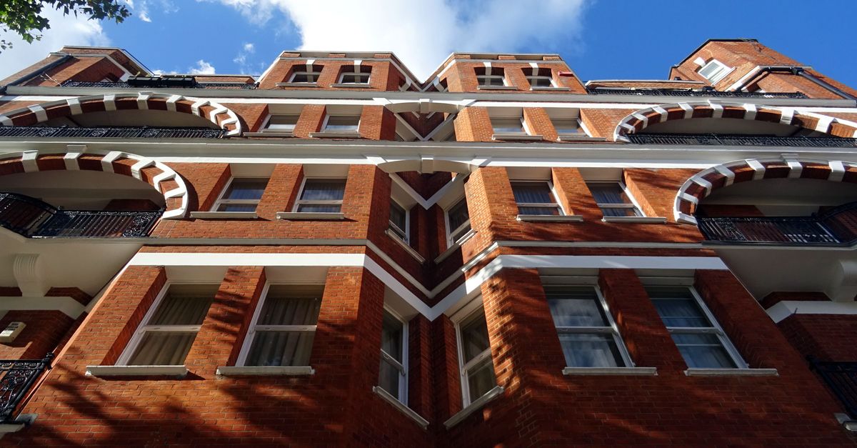 A striking low-angle view of a traditional red brick building under a clear blue sky, showcasing architectural detail.