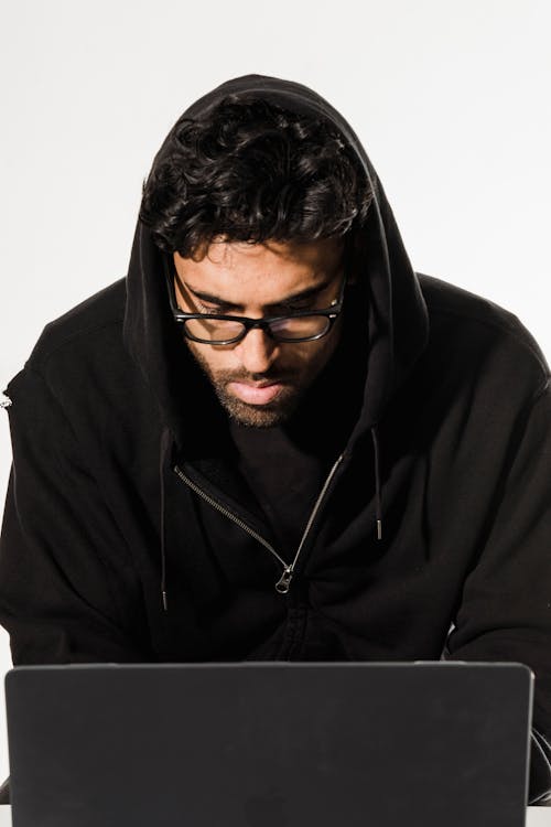 Serious hacker using laptop in workshop