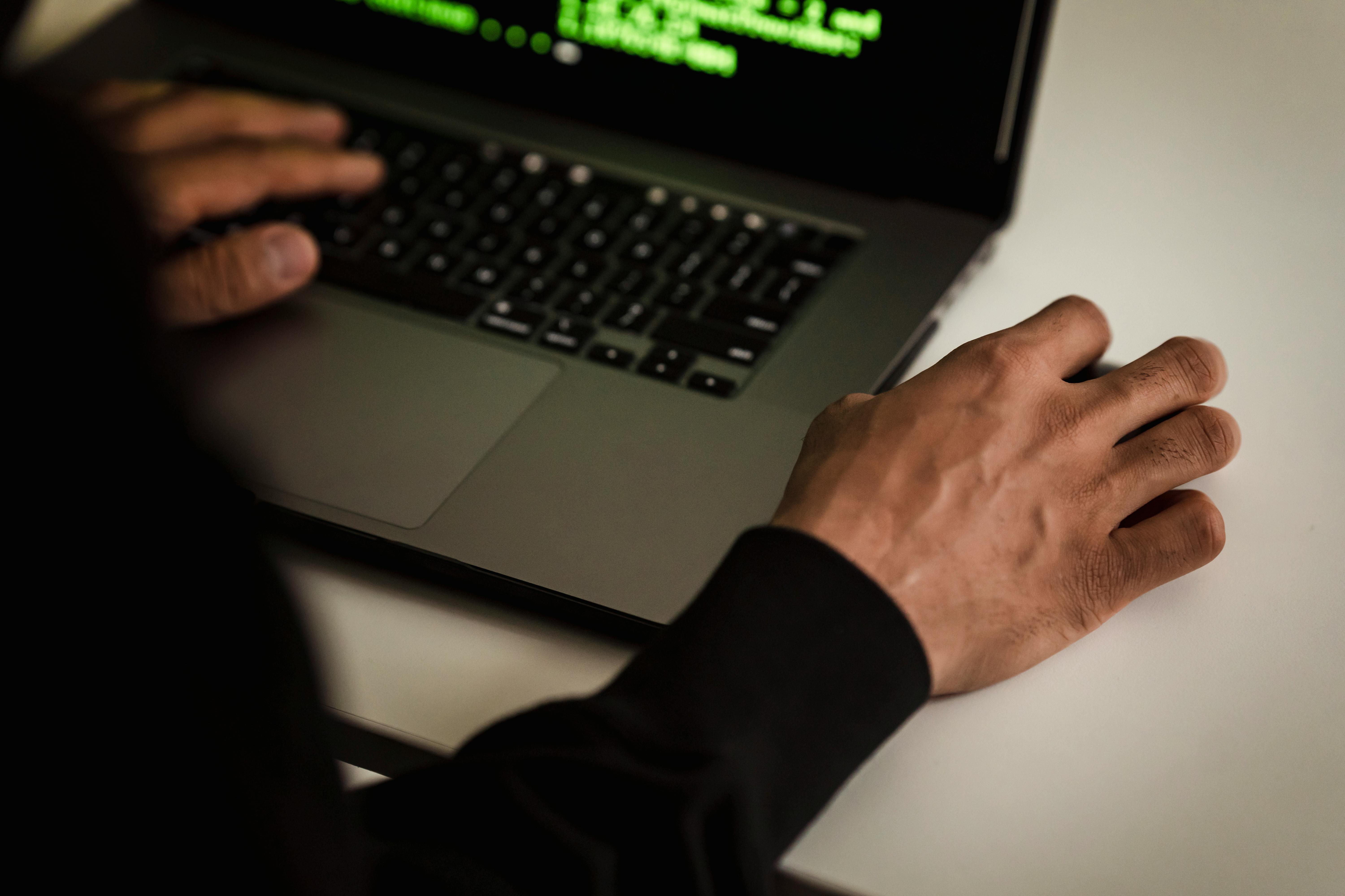 crop unrecognizable male programmer working on laptop in office