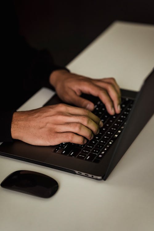 Crop unrecognizable man typing on laptop keyboard