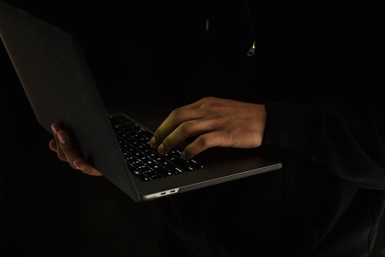 Crop Unrecognizable Man Using Laptop In Darkness