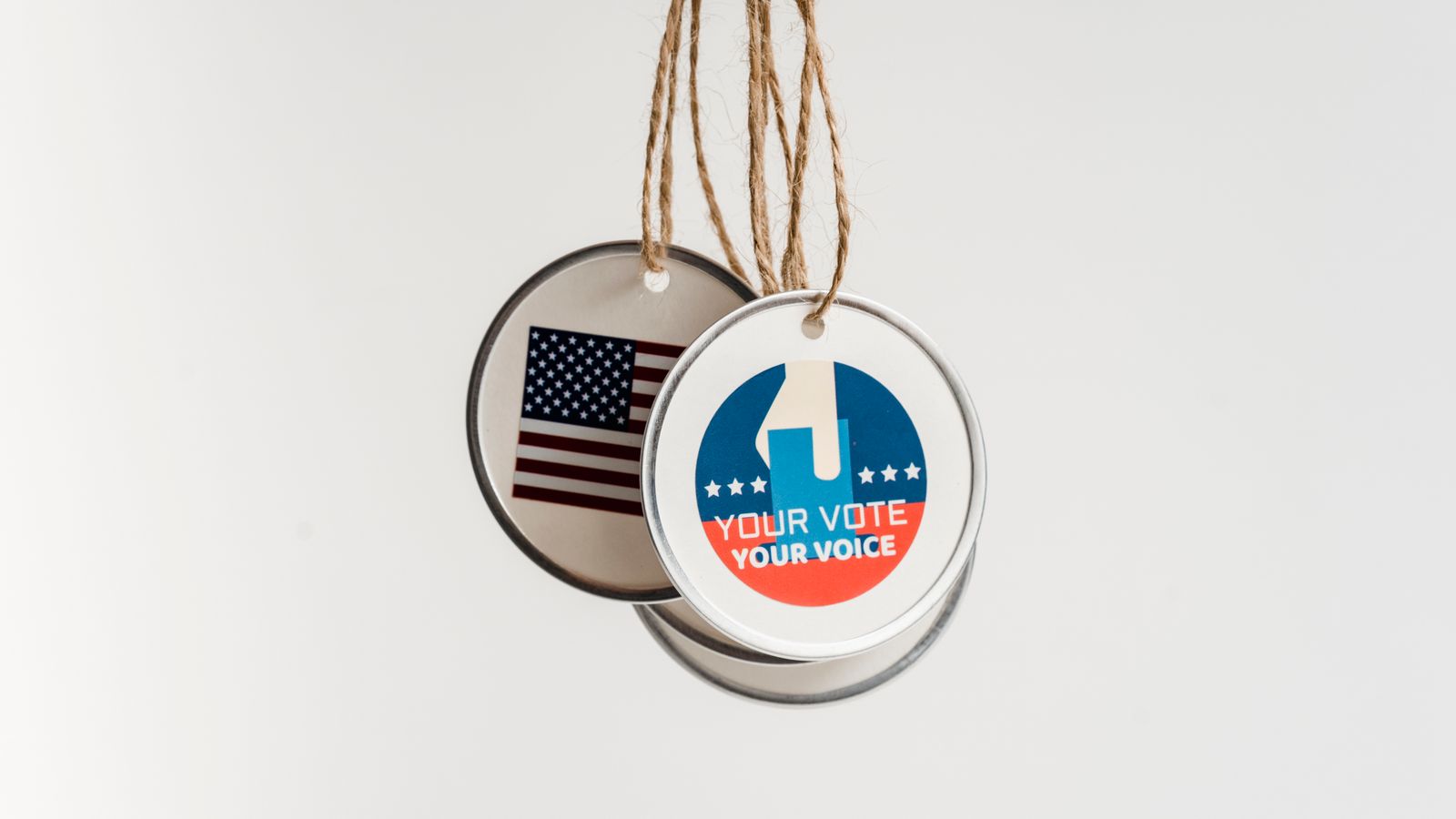 Close-up view of USA voting badges hanging on strings against a white background.