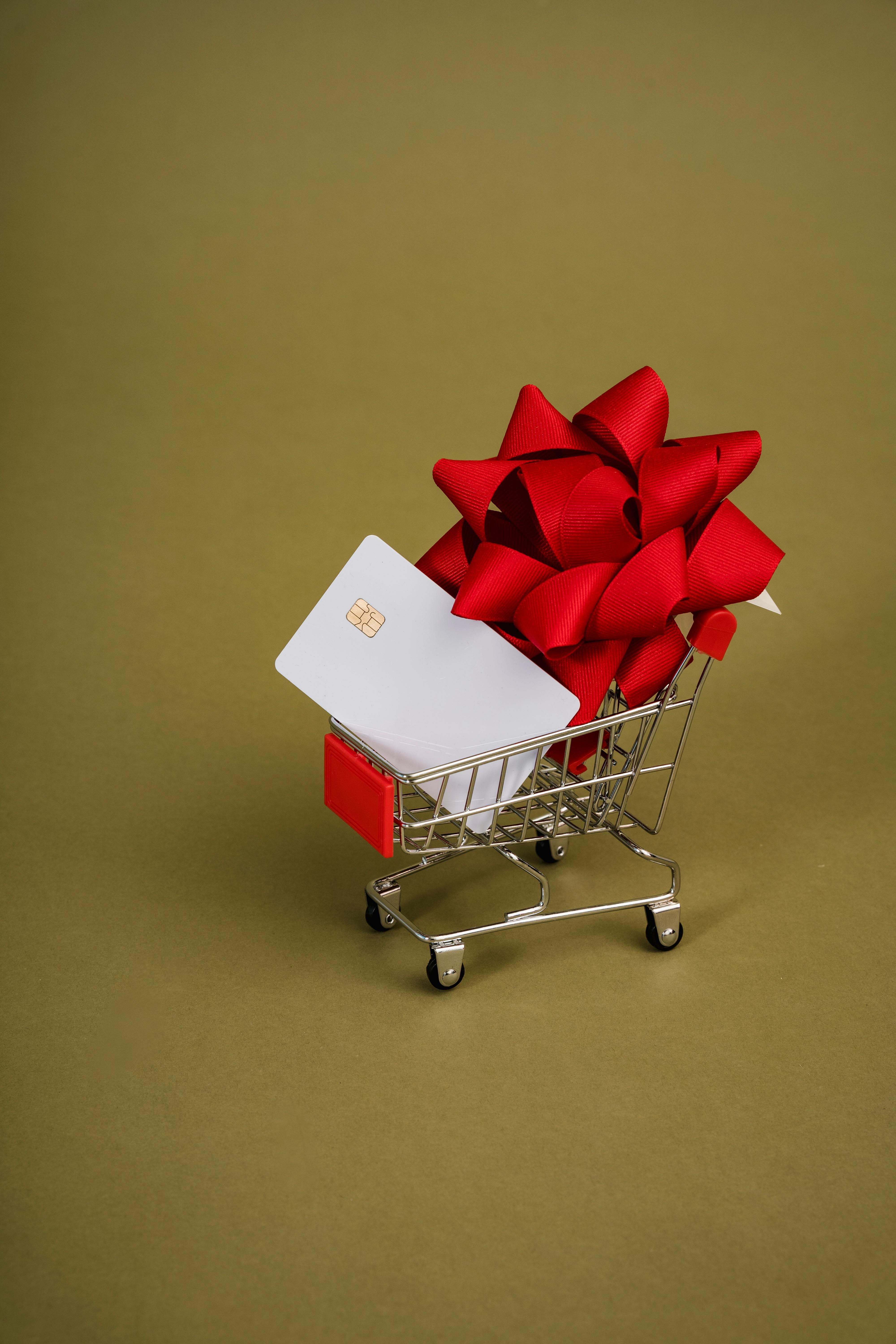 miniature shopping trolley with a red ribbon and a chip card
