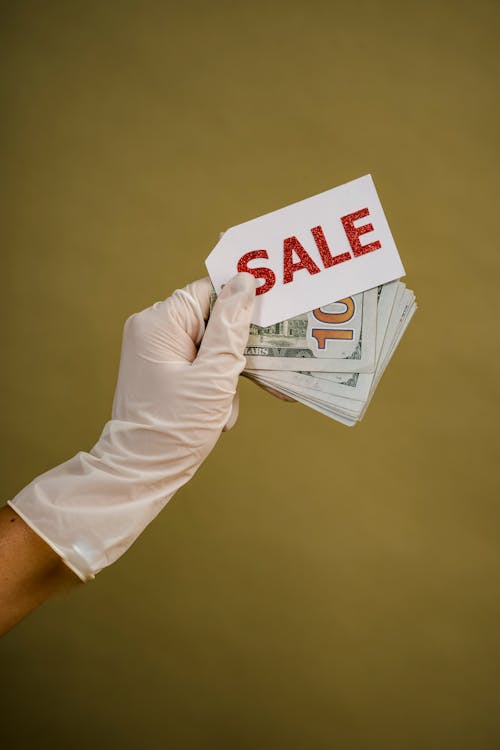 Free A Person Holding Money and a Sale Tag Stock Photo