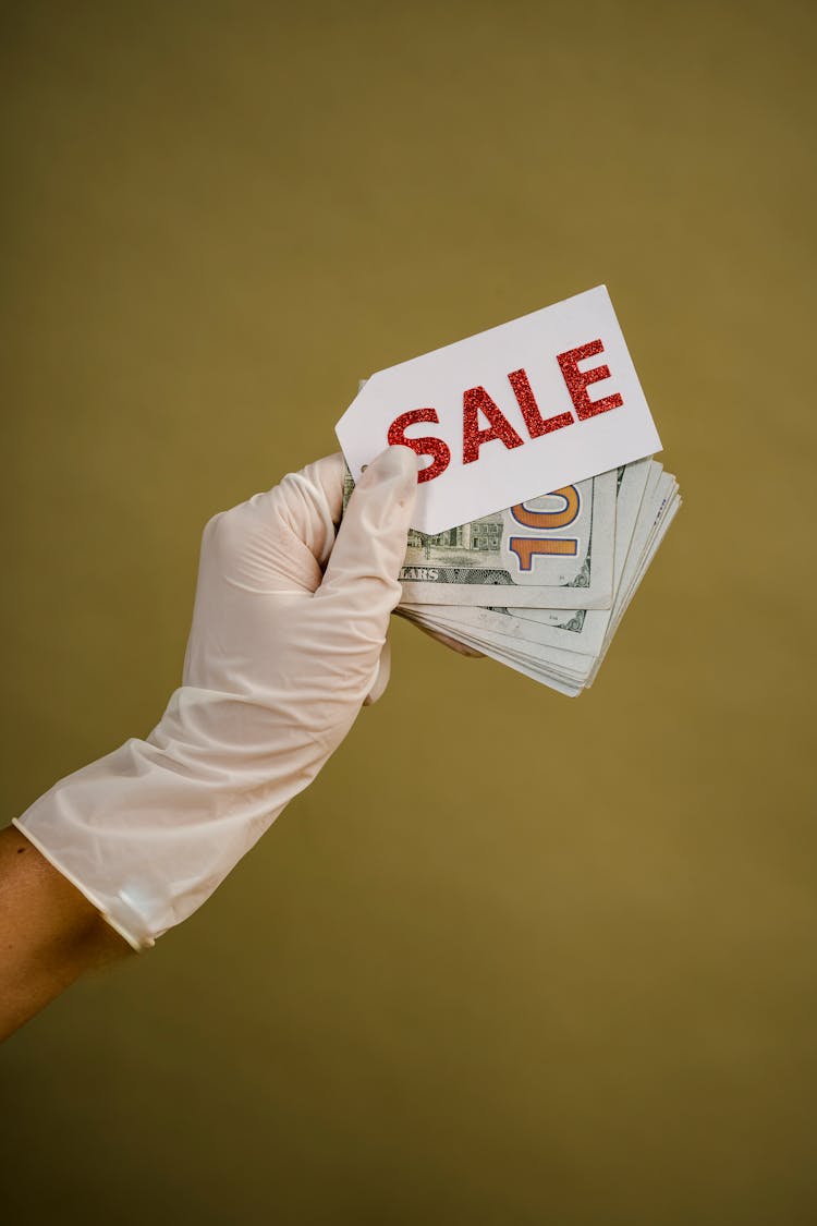 A Person Holding Money And A Sale Tag