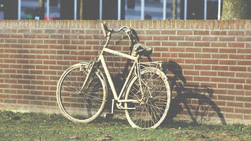 Free Old rusty bicycle leaning on a brick wall with shadow in daylight. Stock Photo