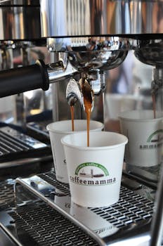 Close-up of espresso dripping into cups from a coffee machine at an indoor café.