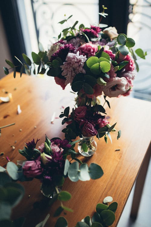 Flower Arrangements In Vases on Wooden Table