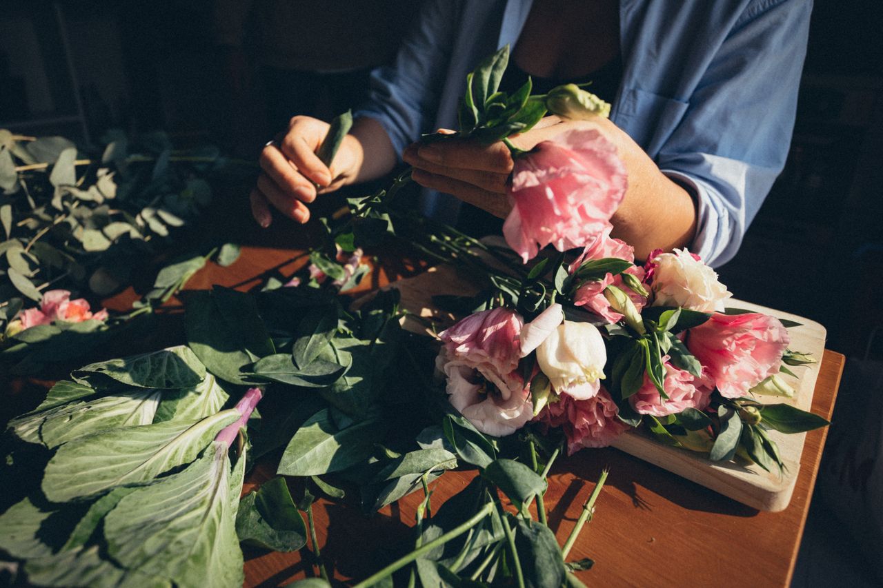 a florist arranging a beautiful bouquet of pink and white flowers usin