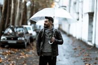 下雨的城市街道上，一名自信的男子撑着透明伞
