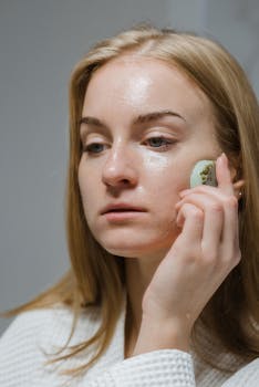 Close-up of a woman using a jade roller for facial massage as part of her skincare routine.