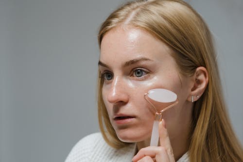 Woman Doing Face Massage With A White Jade Roller