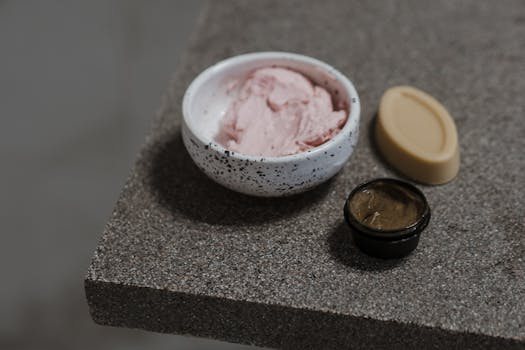 Close-up of a ceramic bowl with pink clay mask and cream, ideal for skincare and self-care routines.