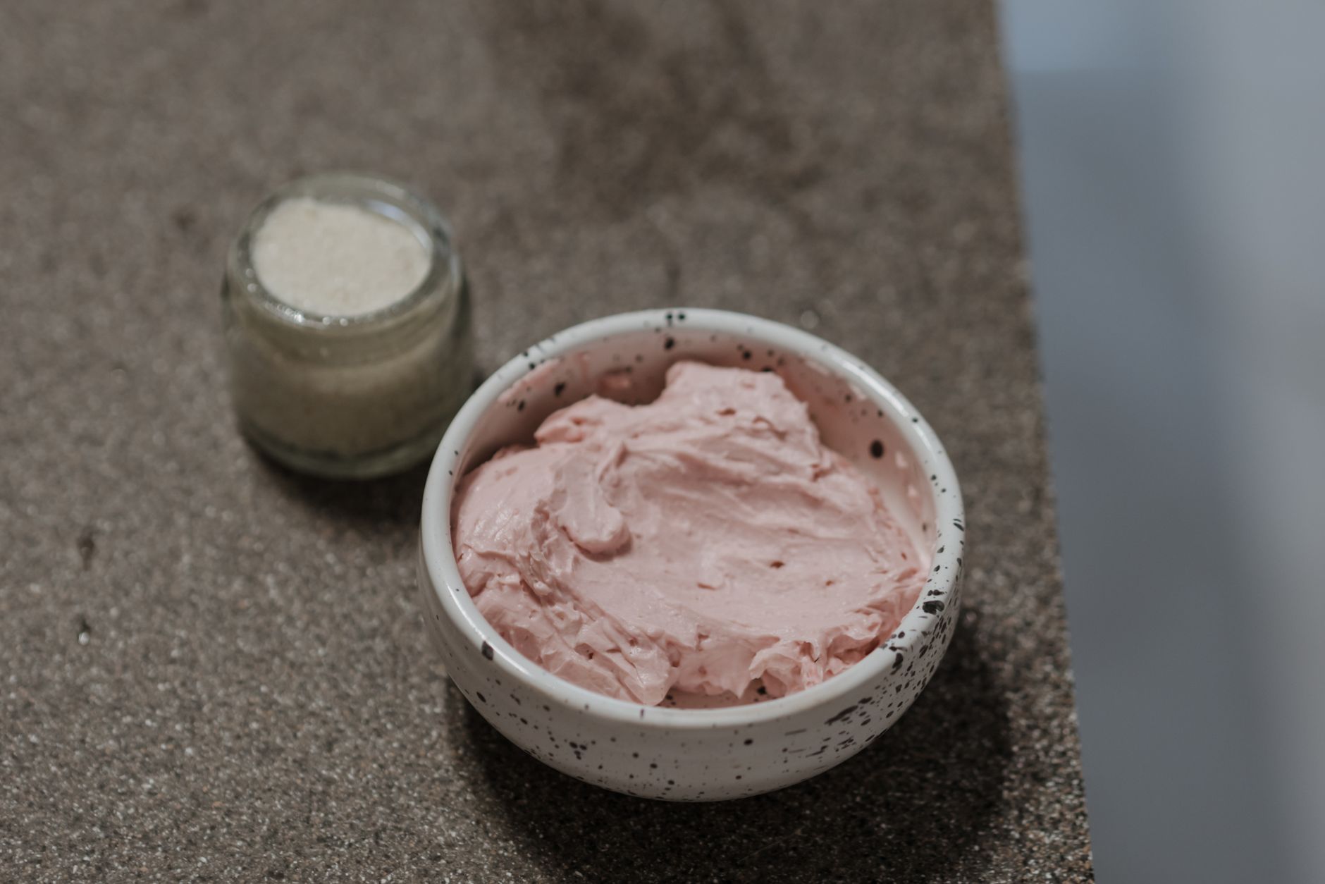 Close-up of a pink clay mask in a ceramic bowl, perfect for skincare routines and self-care.