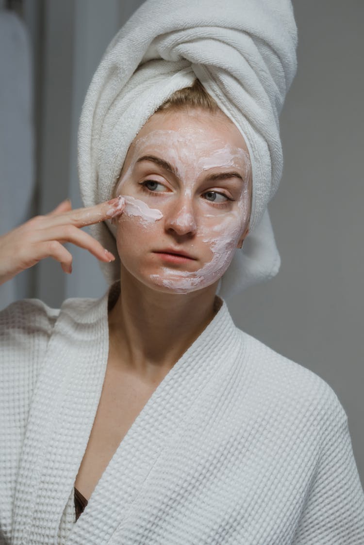 A Woman Applying A Clay Mask On Her Face