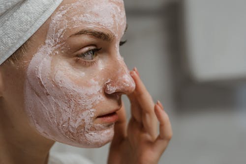 Close-up Photo of a Woman Applying Facial Cream 