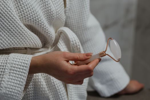 Close-up image of a hand holding a facial roller, ideal for skincare routines and self-care.
