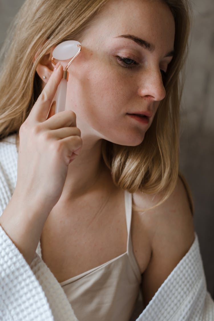 A Woman Massaging Her Face With A Face Roller 