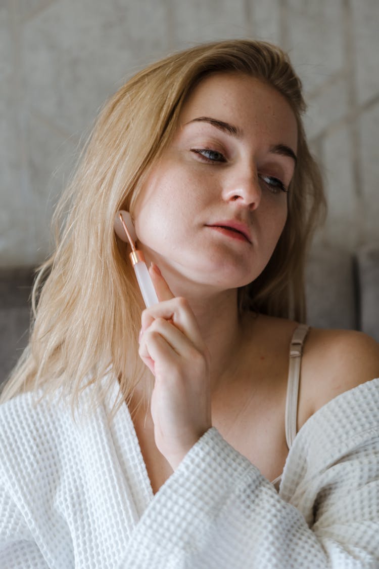 A Woman Using A Face Roller 