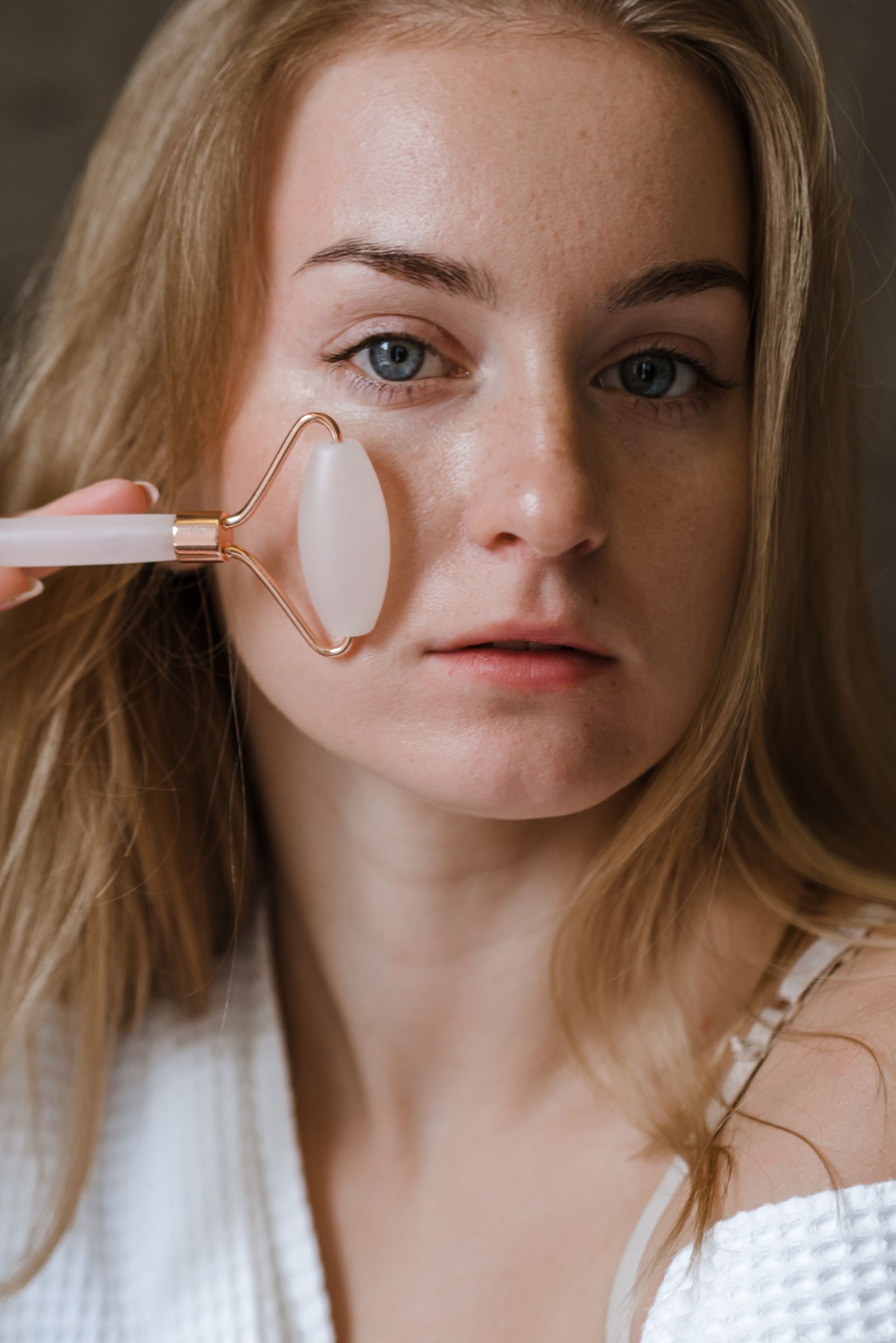 Woman using a facial roller during a calm beauty care routine