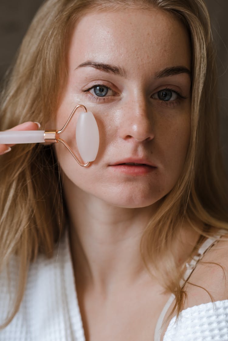 A Woman Using A Face Roller 