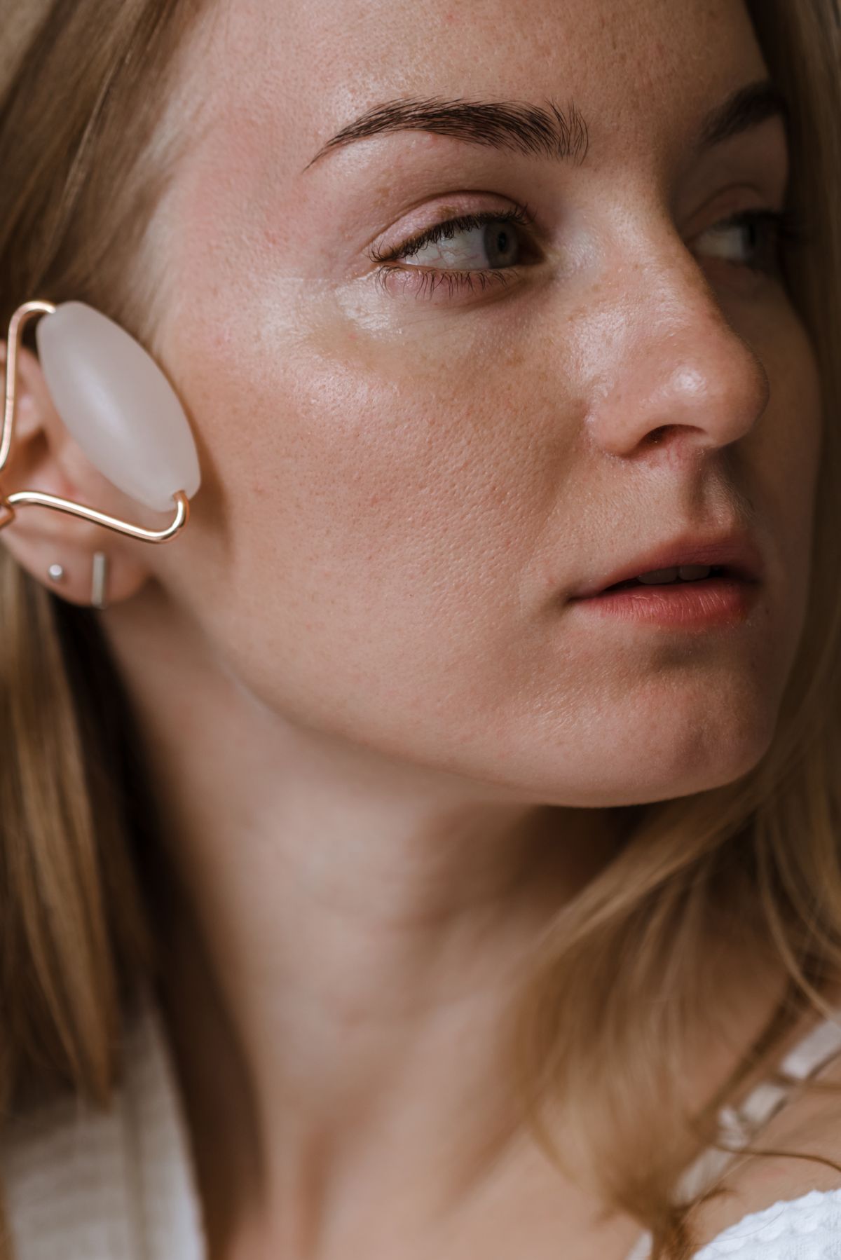 Woman using a facial roller as part of a refined self-care routine