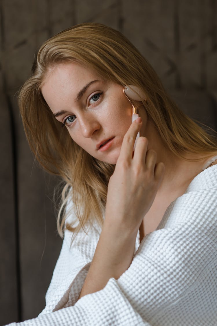 A Woman Using A Face Roller 