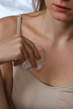 一名女子用刮痧工具护理胸部，注重护肤和自我保养