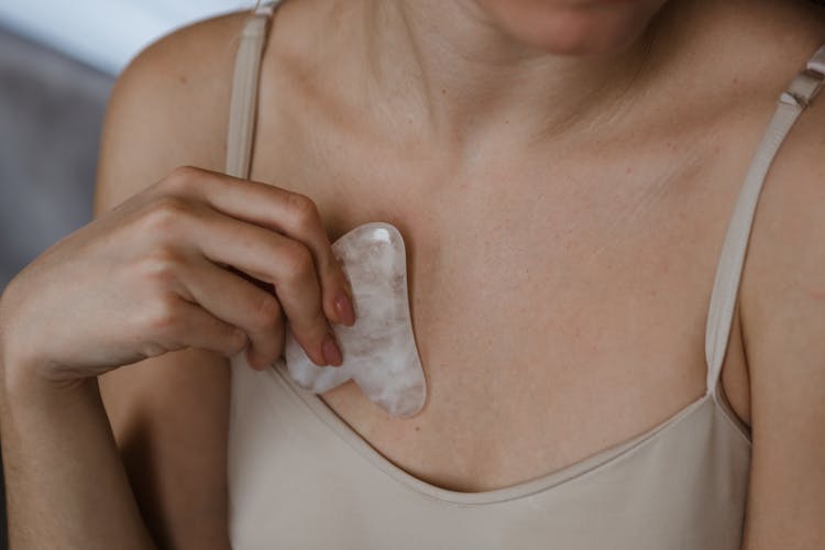 Chest Of A Woman In Spaghetti Strap Using Gua Sha