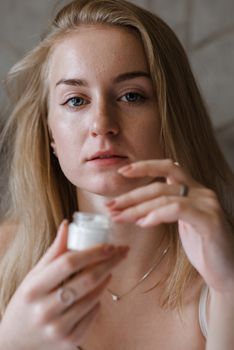 手持护肤霜罐的女性特写，突出美丽与自我护理
