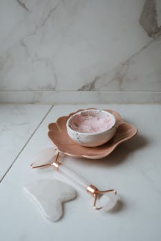Aesthetic arrangement of skincare tools and cream on a marble surface enhancing beauty routines.