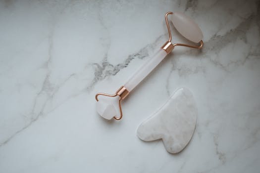 Close-up of a luxurious gua sha and facial roller placed on a marble surface, representing skincare elegance.