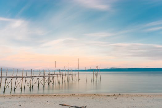 Tranquil view of Luwuk's beach and pier during sunset, showcasing nature's beauty.