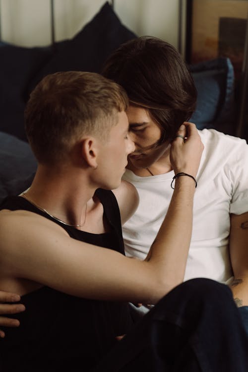 Free Gay Couple Hugging and Sitting by the Bed  Stock Photo
