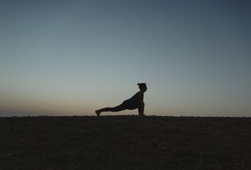 A silhouette of a woman in a yoga pose against a twilight sky, showcasing tranquility and balance.
