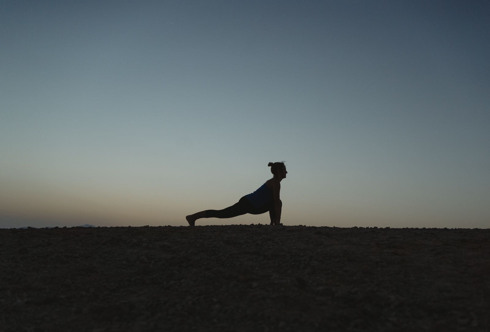 Woman practicing a seated yoga stretch at home in soft evening light