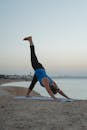 女人在日落时在海滩上练习瑜伽，体现健康灵活的生活方式