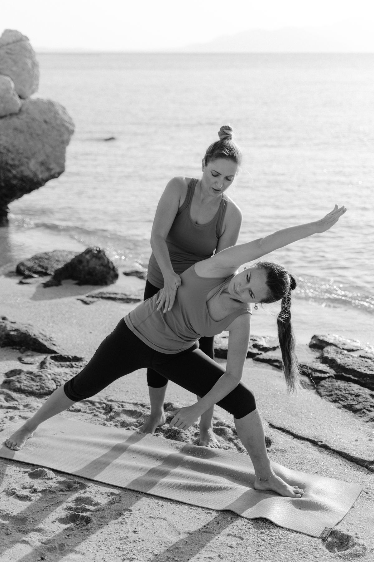 A woman practising yoga on the beach at sunrise