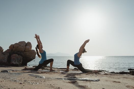 2 Women Jumping on Brown Rock Near Body of Water