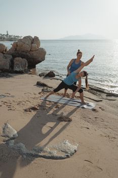 Two women practicing yoga by the sea, enhancing fitness and relaxation.